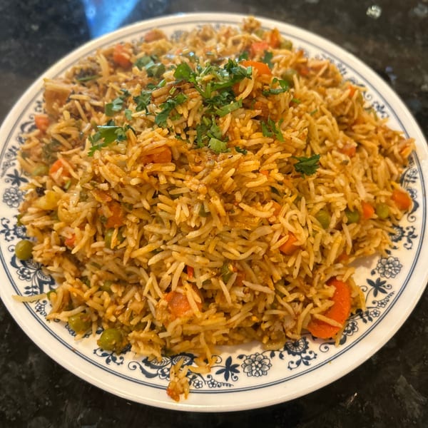 A close-up of Tadka Indian Restaurant's vegetable biryani, garnished with fresh cilantro on a white plate.