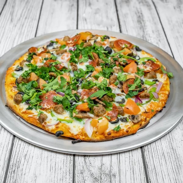 A whole pizza with pepperoni, sausage, olives, peppers, onions, and cilantro on a metal pan.