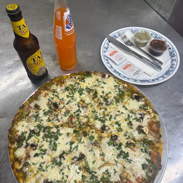 Tadka Indian Restaurant's Indian pizza with cheese and cilantro, alongside beer, soda, and condiments.